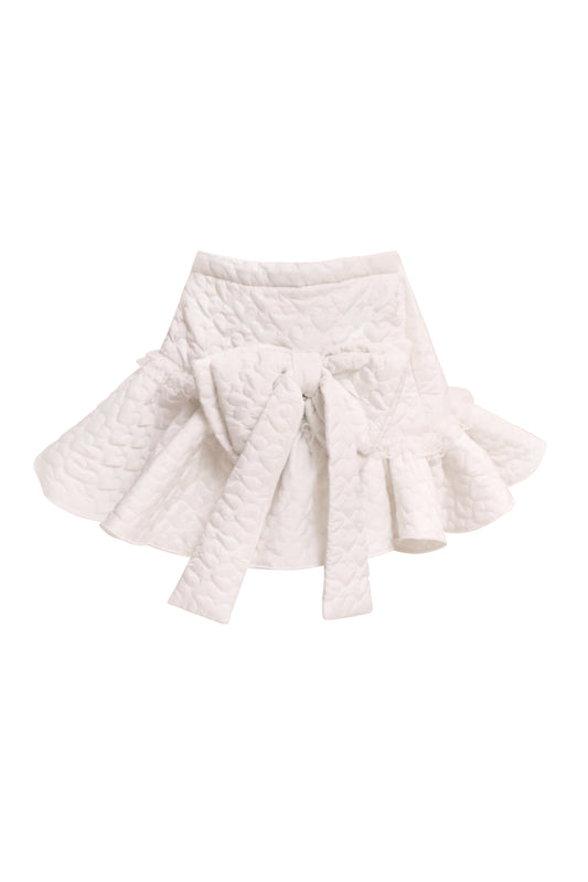 A white, asymmetrical, heart-quilted skirt with frills and lace trim at the hem, made from 100% polyester.